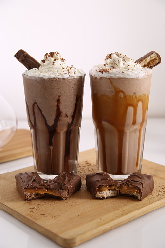 Milk shake blended with ice served with whip cream and chocolate sticks.