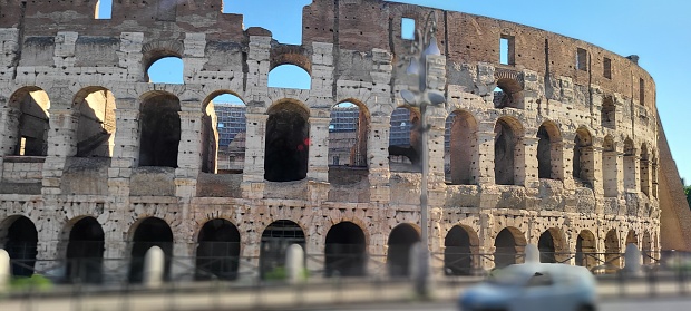 The exterior facade of the Colosseum or Coliseum with the arches against blue sky in Rome, Italy