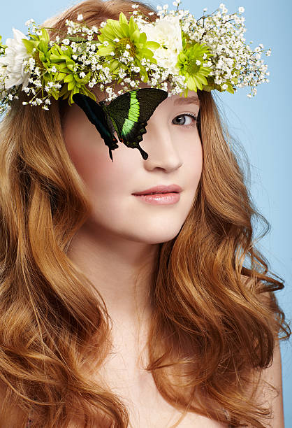 beautiful girl and butterfly portrait of beautiful healthy redhead teen girl with butterfly sitting on her garland on blue papilio palinurus stock pictures, royalty-free photos & images
