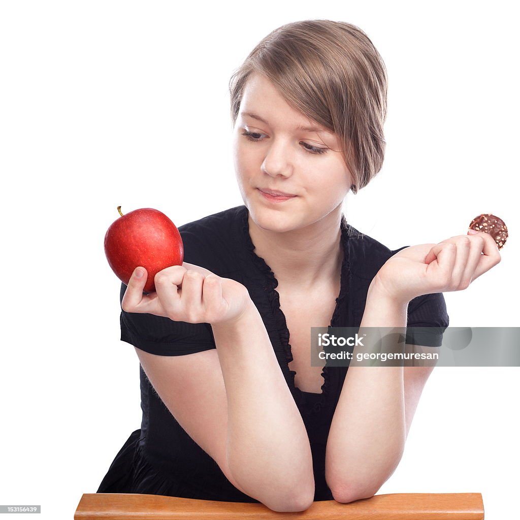 Time for a decision Young woman choosing between apple and chocolate cookies on white background Adult Stock Photo
