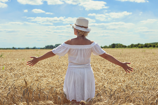 Woman walking through a wheat field on a sunny day