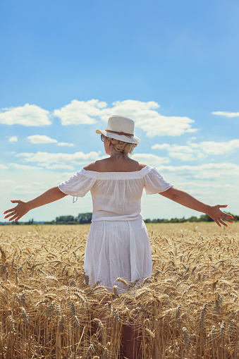 Woman walking through a wheat field on a sunny day