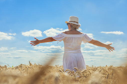 Woman walking through a wheat field on a sunny day