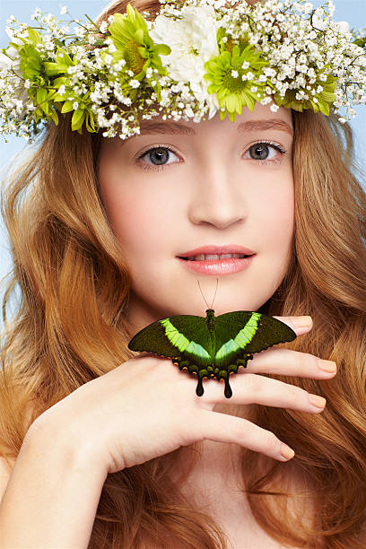 beautiful girl and butterfly portrait of beautiful healthy redhead teen girl in garland with butterfly on hand on blue papilio palinurus stock pictures, royalty-free photos & images
