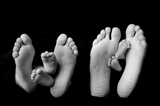 Family of four with bare feet, showing the soles.