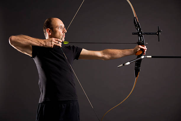 istock Profile of a man dressed in black aiming a bow and arrow  153158496