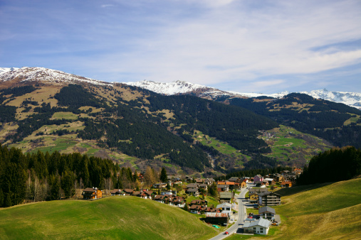 The town of Obersaxen-Affeier in the Swiss Alps (canton of Graubünden). The photograph was taken in early spring not long after the snow had molten so patches of grass are still yellowish-brownish.