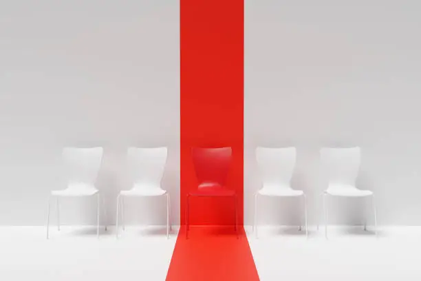 Photo of Highlighted red chair in the middle of a row of white chairs on white background. Illustration of the concept of right candidate in job interviews
