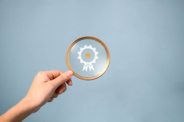 istock Hand holding magnifying glass with virtual certification of quality assurance, Standardization, Good service with five stars, High quality control, Goal achievement, Compliance to regulations 1531607754