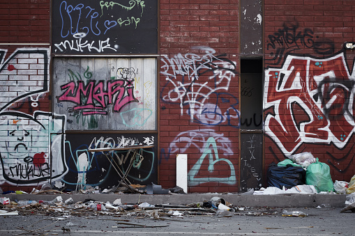 Young male artist painting graffiti on wall outdoors.