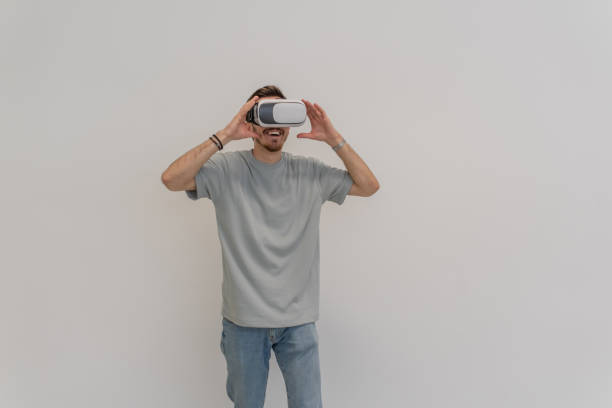 istock Futuristic man wearing virtual reality glasses interacts with the air in an isolated gray background. 1531623128