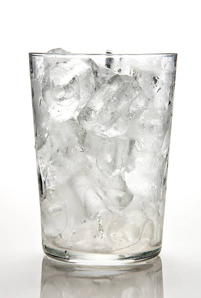 Glass full of ice cubes against a white background stock photo