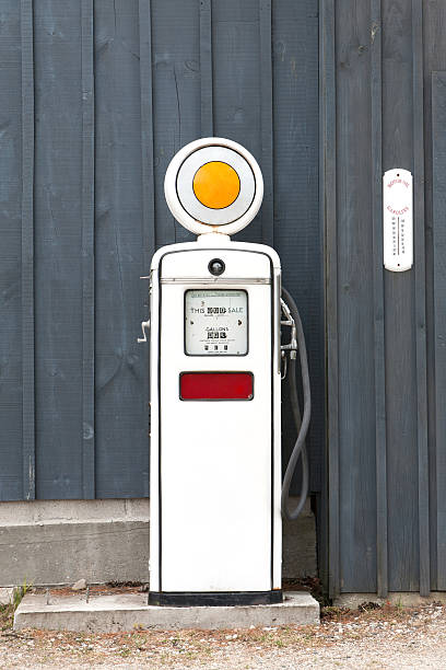 A front view of an old fashioned gasoline pump from the 1960's with 42 1/2 cents per gallon on the meter against a blue board and batten background.