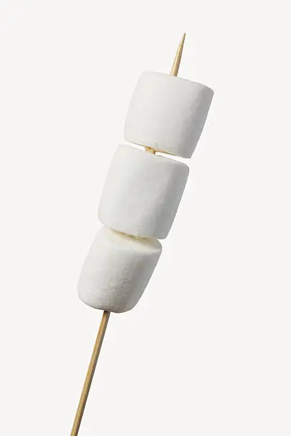 three white marshmallow inside a long wooden stick