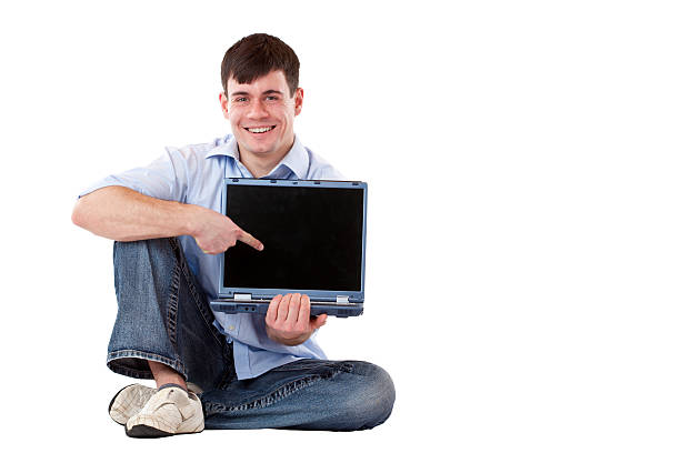 Young, happy, handsome man pointing with finger at computer monitor stock photo