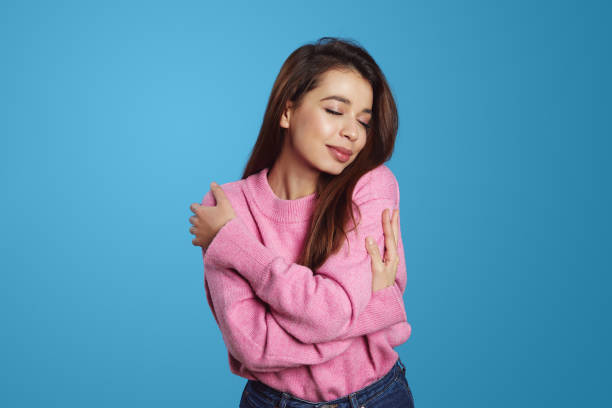 istock Charming cute hispanic girl in pink sweater hugging herself while smiling with closed eyes 1531651483