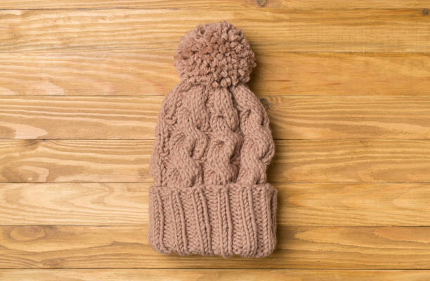 istock Brown winter hat with pompon on wooden background. Top view 1531652079