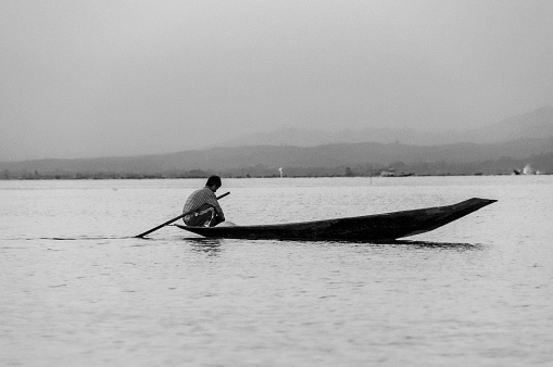 Nyaung  Shwe, Inle Lake, Myanmar - nov 10,2012 : black and white of a canoe at sunset on the calm waters of Inle Lake