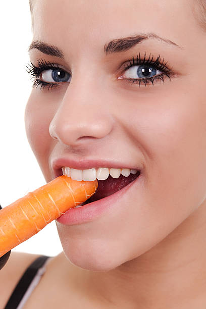 istock woman biting raw carrot 153169605