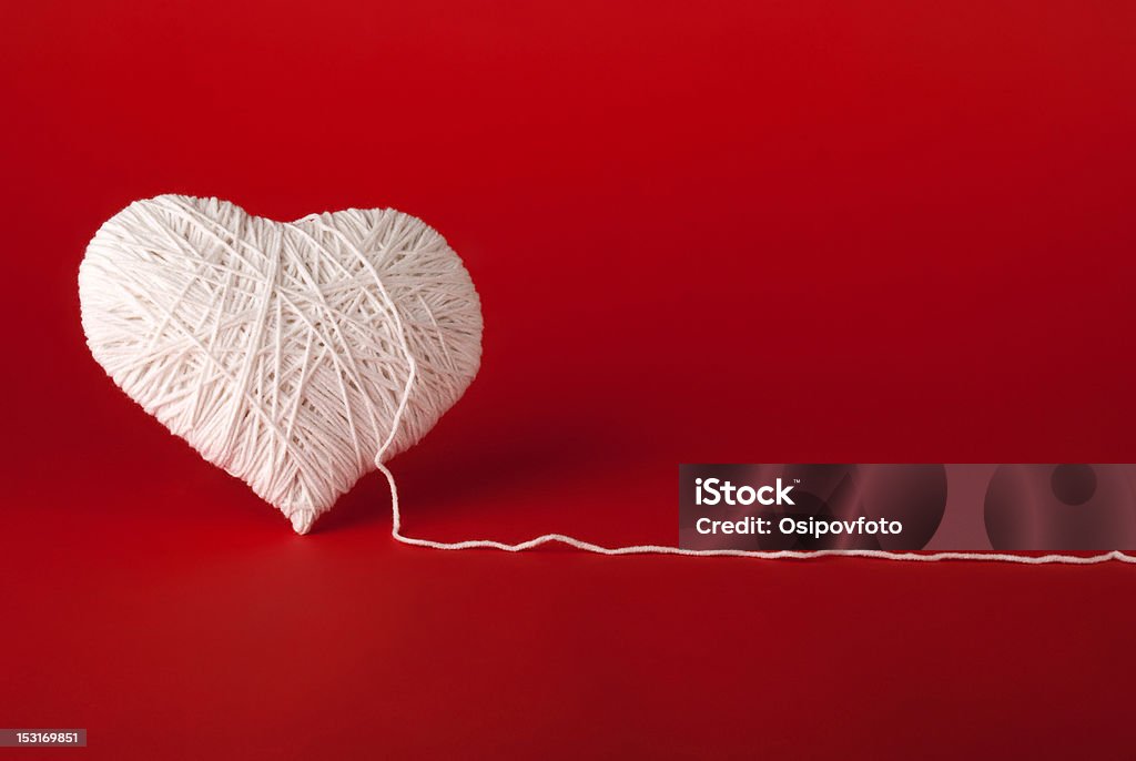 White heart made of wool on a red background White heart made of wool on a red background. Valentine's Day. Colored Background Stock Photo