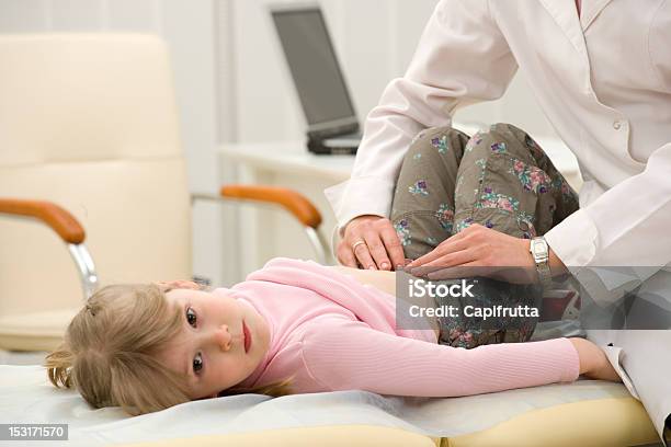 Female Doctor Examining The Stomach Of A Young Girl On Table Stock Photo - Download Image Now