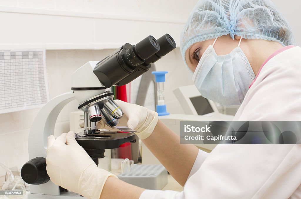 Médico que trabaja con un microscopio - Foto de stock de Abrigo libre de derechos