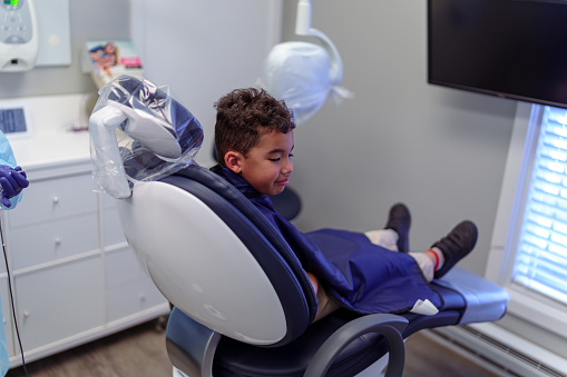 Young, multiracial boy, a pediatric patient, waits excitedly to receive a x-ray scan during his dentist appointment.