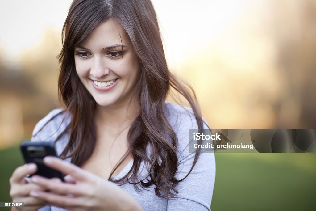 Красивая улыбающаяся женщина, отправив сообщение с ее телефона - Стоковые фото 20-29 лет роялти-фри