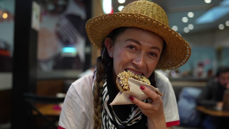 Mid adult woman eating doughnut in the airport restaurant