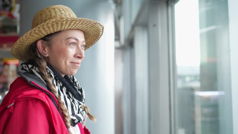 Mid adult woman looking through window at the airport