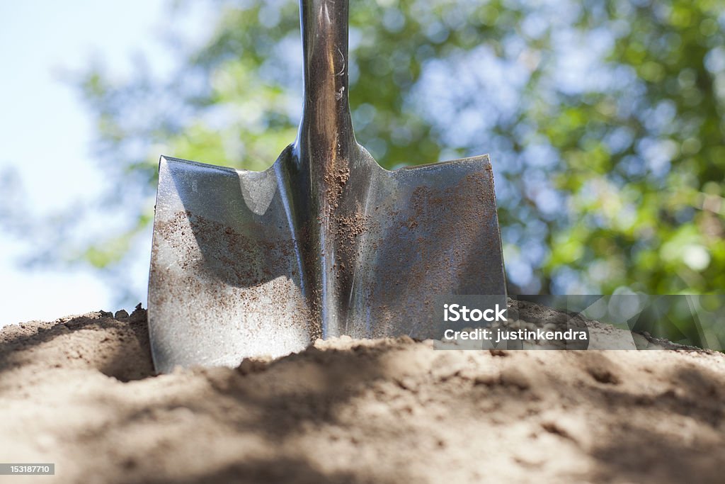 Shovel and Dirt A shovel is stuck in a pile of dirt with bokeh in the background. Shovel Stock Photo