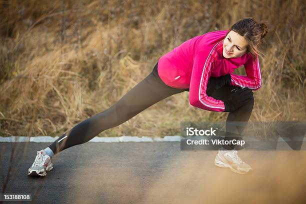 Young Woman Performing Runner Stretch On A Sidewalk Stock Photo - Download Image Now