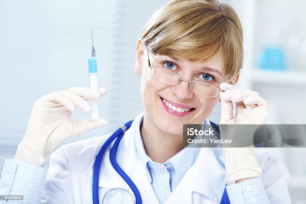 young female doctor Portrait of female doctor smiling with syringe in hand in hospital Adult Stock Photo