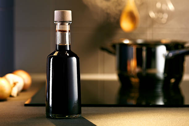 Balsamic vinegar bottle in a kitchen Vinegar in front of hob with steaming pot balsamic vinegar stock pictures, royalty-free photos & images