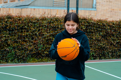 Sports and basketball. A young teen girl plays basketball bouncing the ball. Copy space