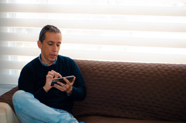 istock Middle-aged man resting on his couch while at home and using his smartphone to send text messages 1531957249
