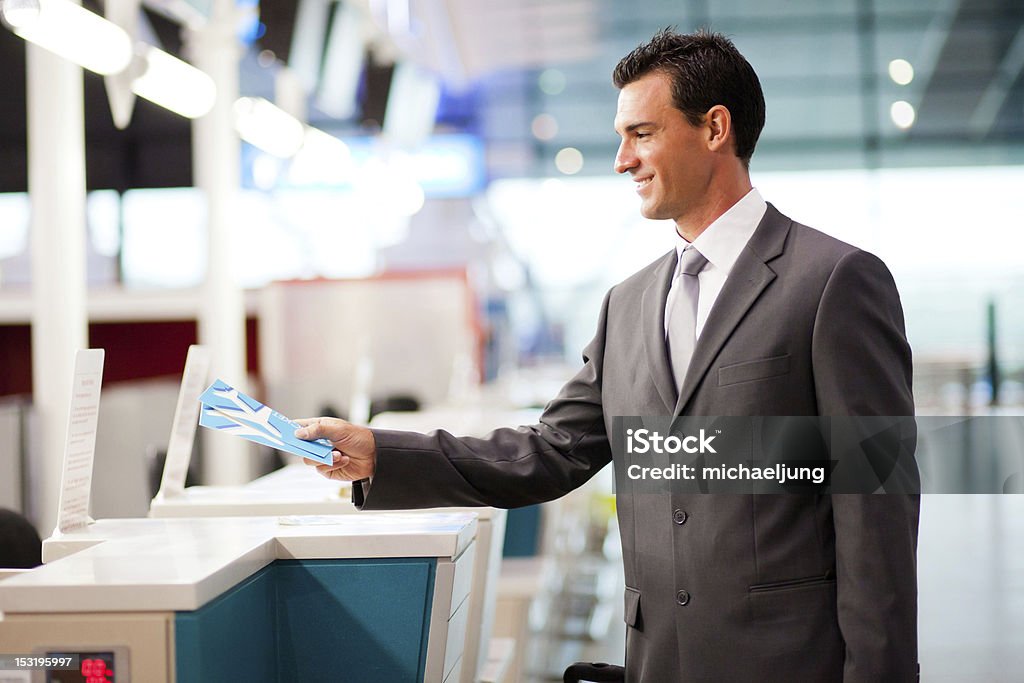 businessman handing over air ticket at airline check in counter handsome businessman handing over air ticket at airline check in counter Airport Check-in Counter Stock Photo