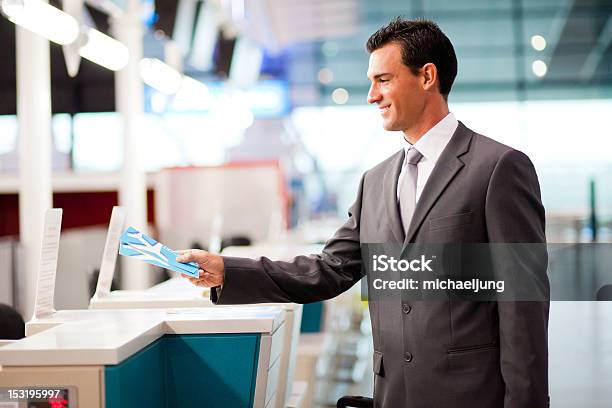 Businessman Handing Over Air Ticket At Airline Check In Counter Stock Photo - Download Image Now