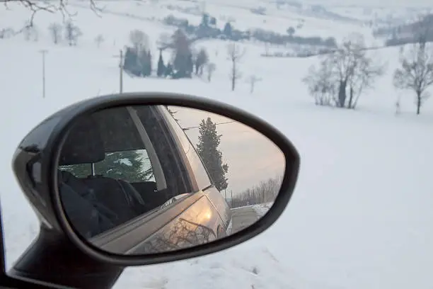 Sunset in the rearviewmirror of an automobile, in winter background
