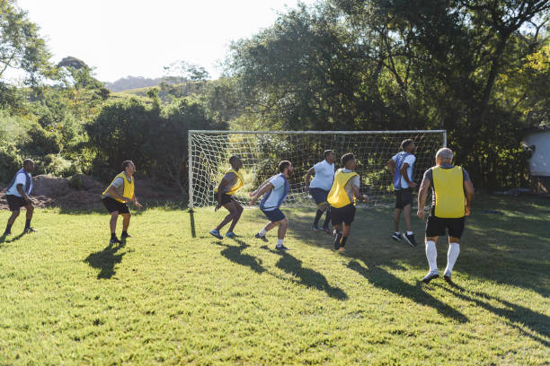 co-workers playing a casual soccer match on sunday - friendly match imagens e fotografias de stock