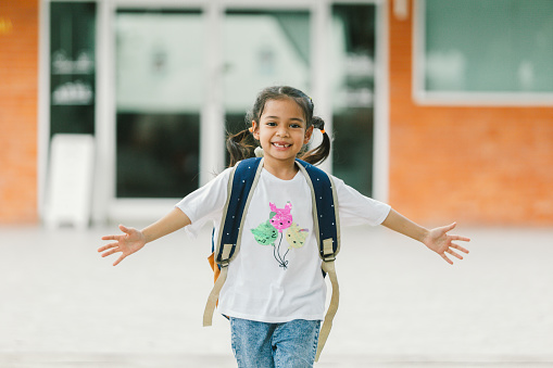 Portrait of happy asian little girl with backpack in the school