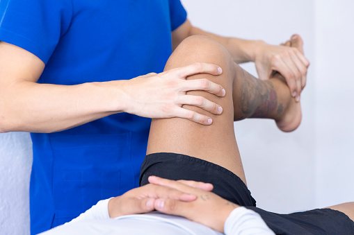 Physiotherapist checking the functionality of his patient's legs.