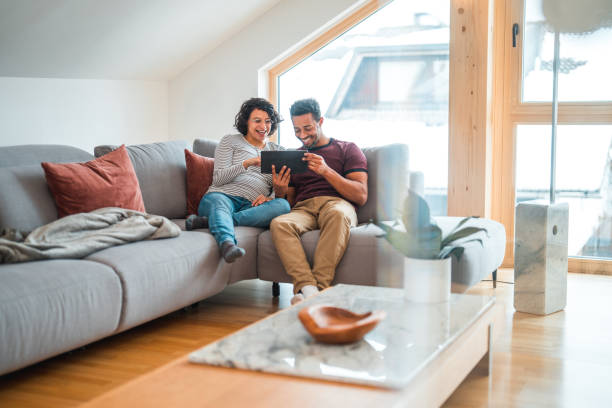 istock Black And Hispanic Pregnant Couple Relaxing At Home, Using Wireless Technology 1532000830