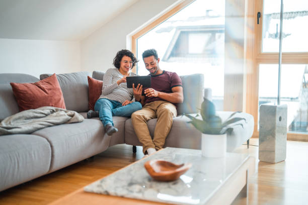 istock Mid Adult Multi-Ethnic Pregnant Couple Relaxing At Home, Using Wireless Technology 1532001343
