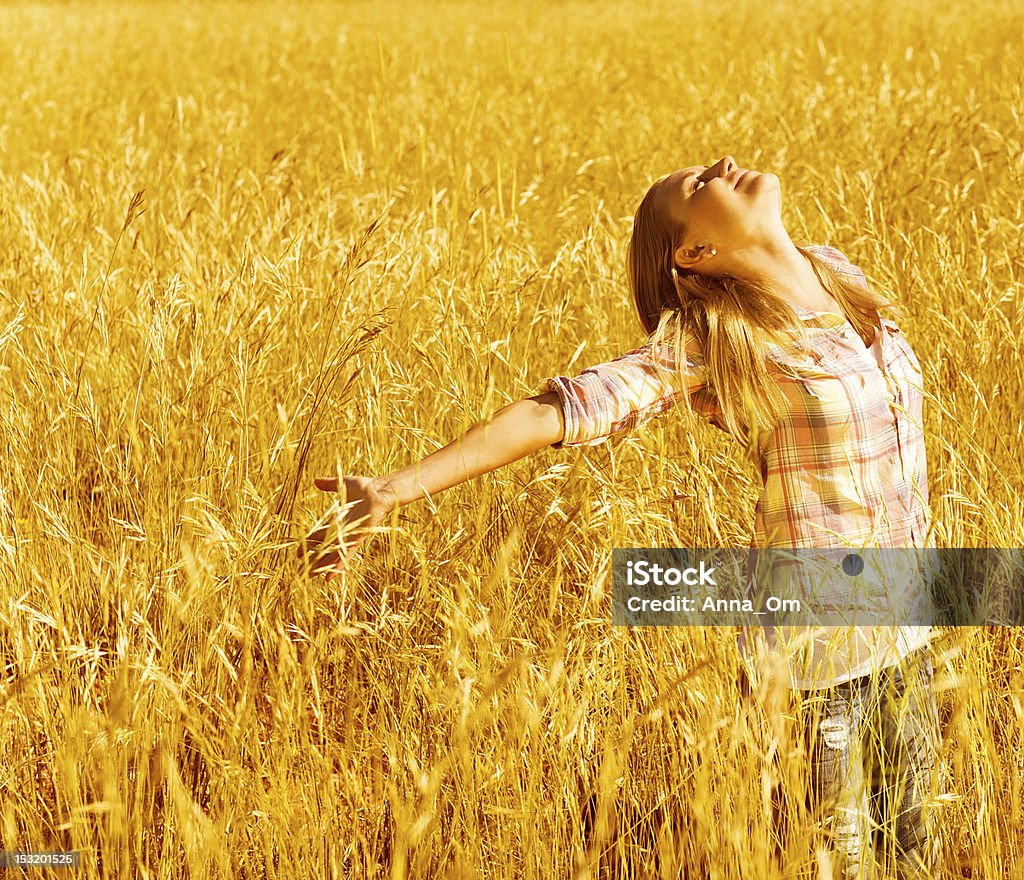 Happy woman on wheat field Picture of cheerful teenager having fun in countryside, cute happy female standing on wheat field with raised open hands and looking up, blond girl enjoying autumn nature, fall season Activity Stock Photo