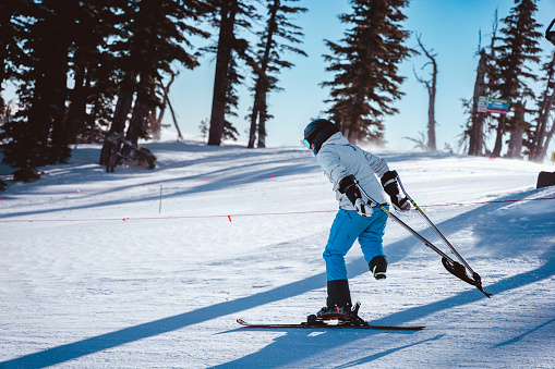 Side view of an elite level athlete 3T/three tracking adaptive skiing on a sunny winter day.