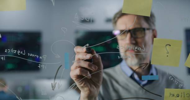 istock Mature financial analyst draws on glass wall with sticky notes 1532028773