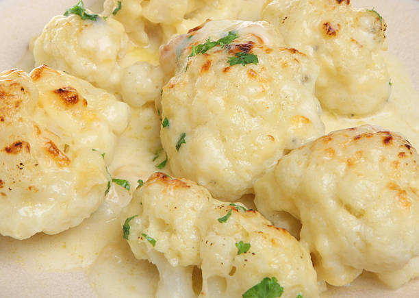 Cauliflower Cheese A plate of freshly baked cauliflower cheese. cheese sauce stock pictures, royalty-free photos & images