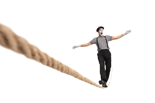 Excited mime walking on a tightrope isolated on white background