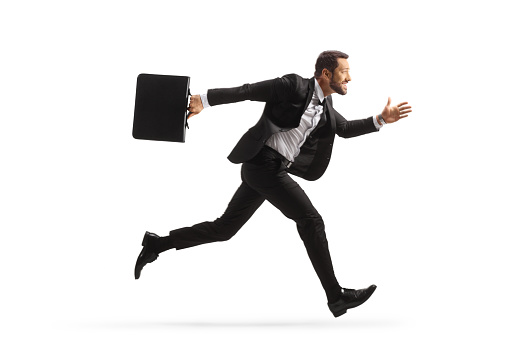Full length profile shot of a businessman running fast and carrying a briefcase isolated on white background